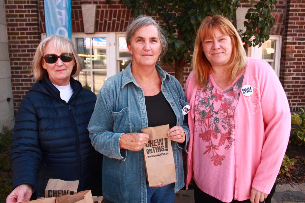 <p>From left, Ellen Brownbill, Diane Milan, and Kelly Knott took part in the Chew on This! poverty awareness campaign Tuesday afternoon outside the Picton Library.</p>
