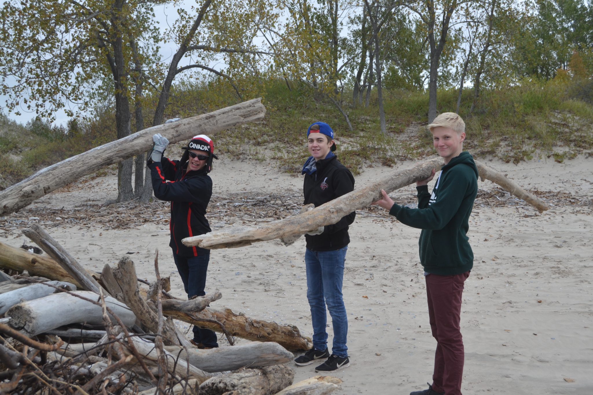 <p>PECI Venture Students (From Left) Thomas Davies, Nolan Steen and Max Lindsay clean up drift wood at Sandbanks Provincial Park Friday. (Jason Parks/Gazette staff)</p>
