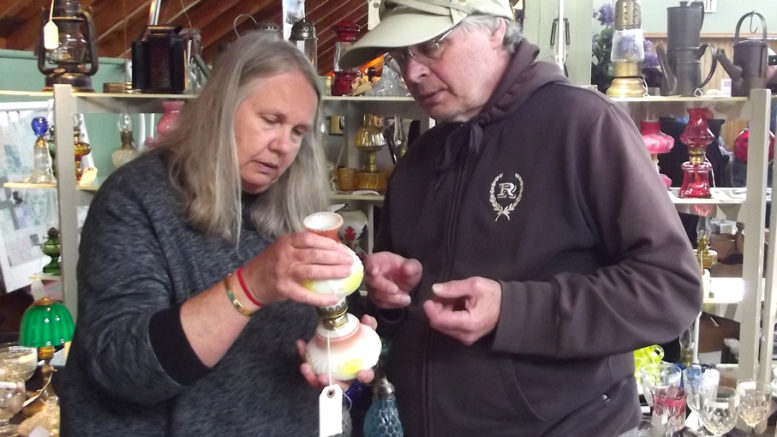 <p>Attracting interest -Gwen Chvalevich of Shadyside Investments of Stouffville shows one of her collectible oil lamps to potential customer John Gorman of Trenton during the Victoria Day weekend Spring Antique Show and Sale at Picton’s Crystal Palace. (Terry McNamee/For The Gazette)</p>
