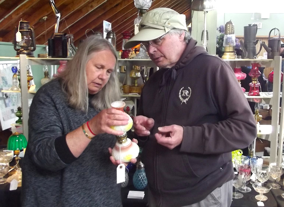 <p>Attracting interest -Gwen Chvalevich of Shadyside Investments of Stouffville shows one of her collectible oil lamps to potential customer John Gorman of Trenton during the Victoria Day weekend Spring Antique Show and Sale at Picton’s Crystal Palace. (Terry McNamee/For The Gazette)</p>
