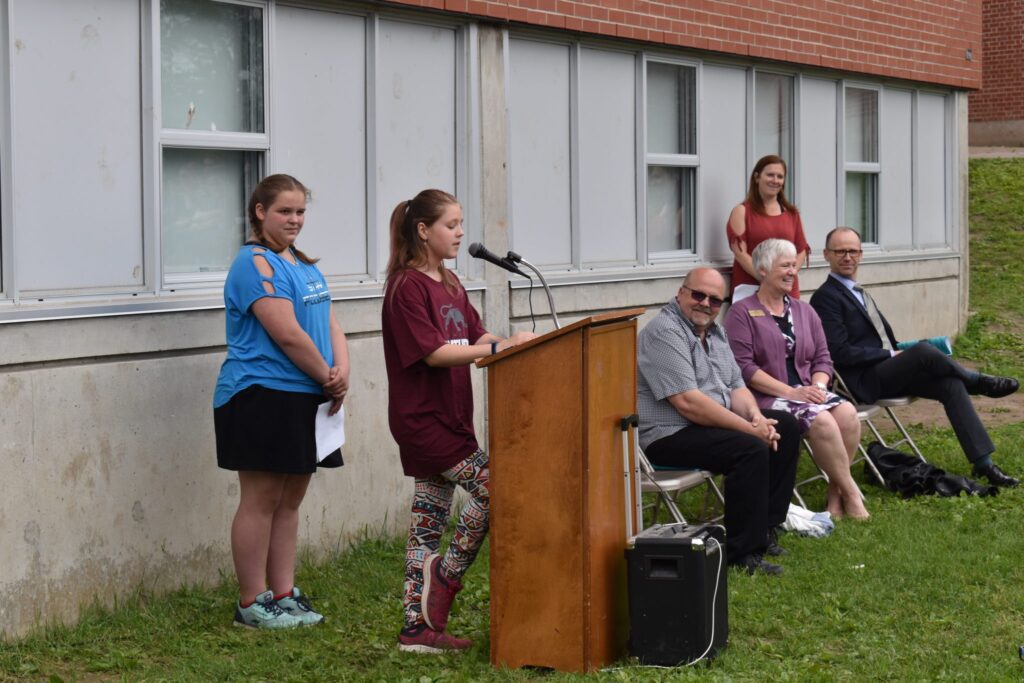 <p>CLOSING TIME- Queen Elizabeth student Yvie Williams speaks about her time at the Picton elementary school while (Left) alumnus Kayla Zachariah, Hastings and Prince Edward District School Board Trustee Dwayne Inch, Director of Education Mandy Savery-Whiteway, PECI Principal Darren MacFarlane and (Standing) Queen Elizabeth Principal Kym Myderwyk look on. (Jason Parks/ Gazette Staff)</p>
