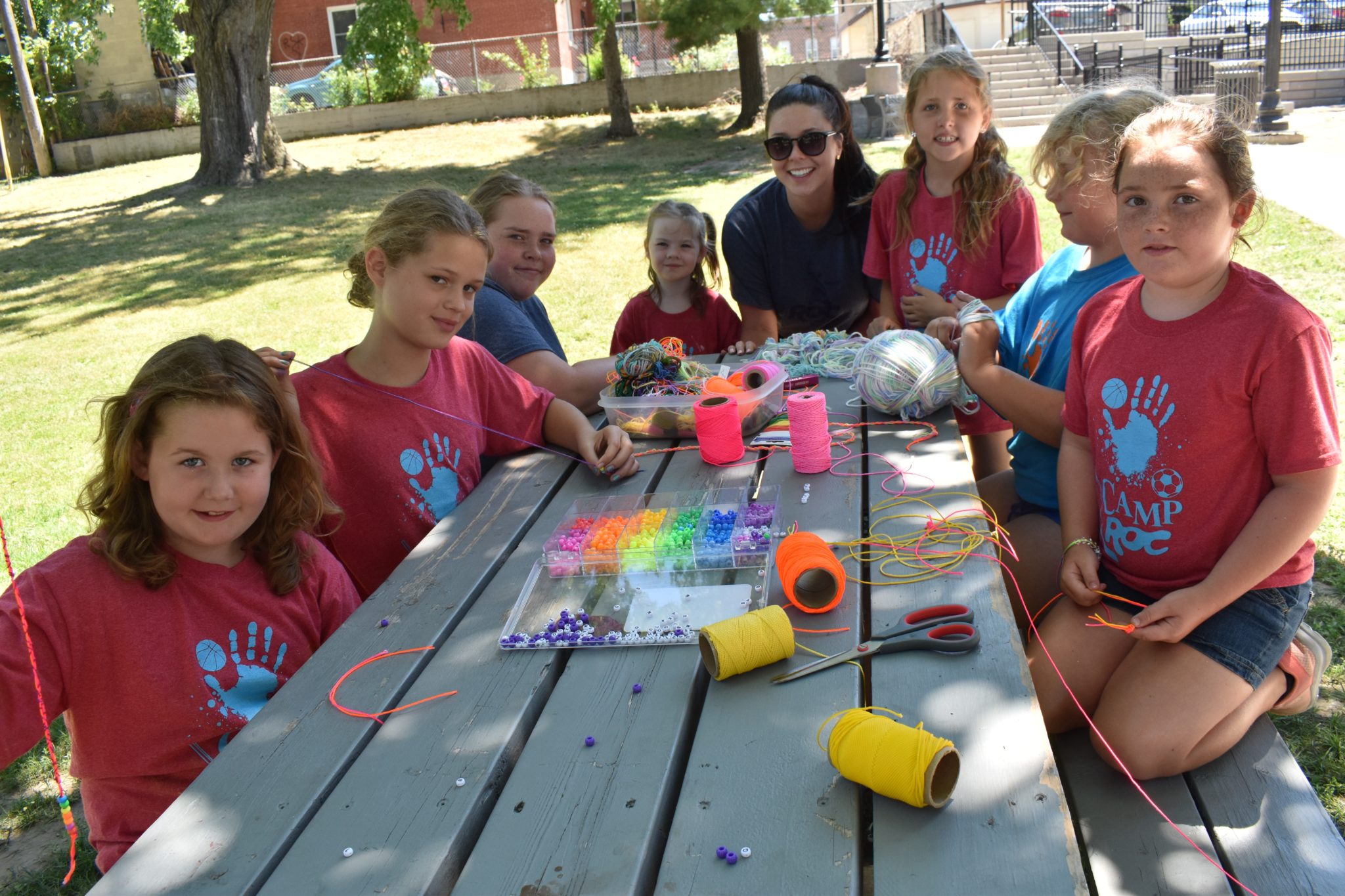 <p>(Centre) ROC Program Coordinator Sydney Kerr and some Camp ROC participants take a break from creating beaded necklaces at Benson Park in 2018.<br />
(Jason Parks/Gazette Staff)</p>
