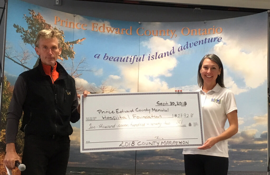 <p>Running tally – On the occasion of its 15th annual race, the County Marathon committee contributed $2,791.81 to the Prince Edward County Memorial Hospital Foundation, bringing its total to $12,331.47. Here, committee member Mark Henry makes the presentation to the foundation’s executive director Shannon Coull following the day’s racing festivities Sunday afternoon.  (Submitted photo)</p>
