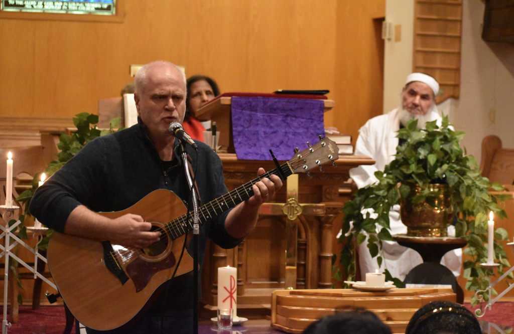 <p>SINGING FOR PEACE- Rev. Joe Ramsey performs ‘Sing it Louder’ at the Bloomfield Peace Vigil at Bloomfield United Church on Friday evening while Rev. Dr. Aruna Alexander and Imam Mohammad Saleh listen on. (Jason Parks/Gazette Staff)</p>
