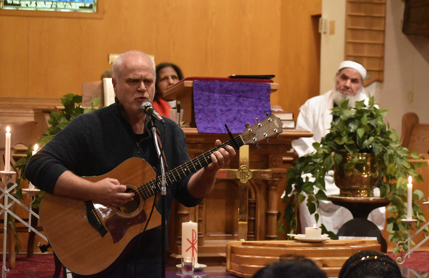 <p>SINGING FOR PEACE- Rev. Joe Ramsey performs ‘Sing it Louder’ at the Bloomfield Peace Vigil at Bloomfield United Church on Friday evening while Rev. Dr. Aruna Alexander and Imam Mohammad Saleh listen on. (Jason Parks/Gazette Staff)</p>

