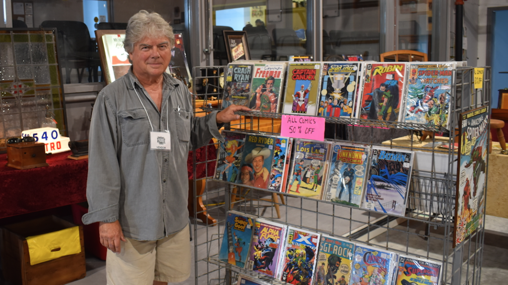 <p>COMICS GALORE – Vendor Peter Neilly stands beside his comics stand on the last day of the annual Antique, Vintage and Retro Show and Sale. (Sarah Williams/Gazette Staff)</p>
