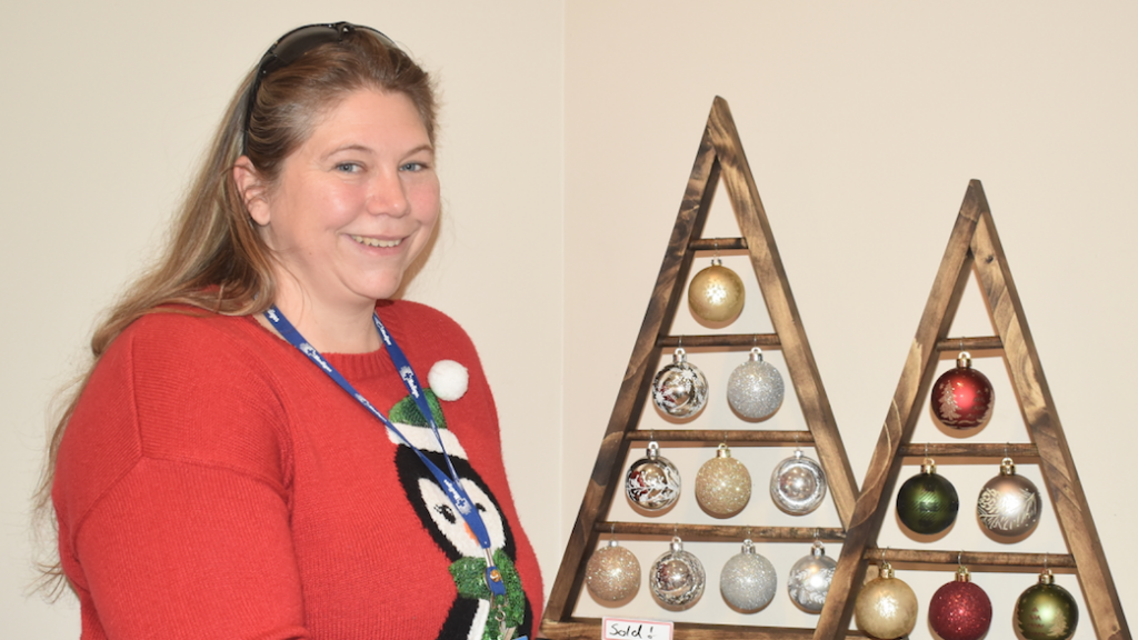 <p>START OF THE SEASON – Acting Resident Quality Supervisor Ulana Orrick stands next to some of the trees made by residents for their annual Christmas Bazaar. (Sarah Williams/Gazette Staff)</p>
