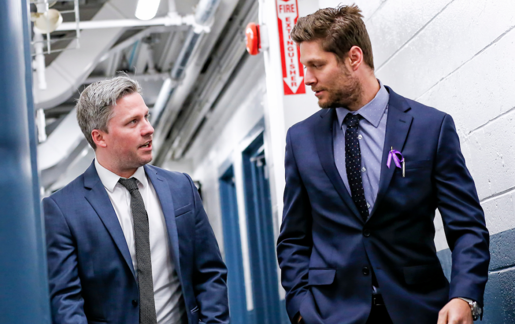 <p>(Right) 2019-20 OJHL Coach of the Year Derek Smith speaks with assistant Sean Turner prior to an October, 2019 game against the Trenton Golden Hawks. (Amy Deroche/OJHL Images)</p>
