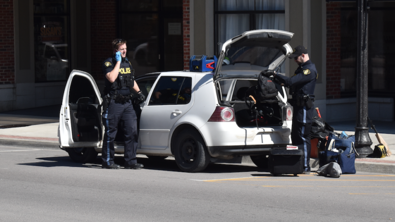<p>STOP AND GO- Provincial Constables (From left) Aaron Miller and Marc Daneau search a vehicle on Main Street in Picton Monday afternoon. A quantity of suspected illicit drugs, weapons, cannabis accessible to the driver and unsealed alcohol were found. (Jason Parks/Gazette Staff)</p>
