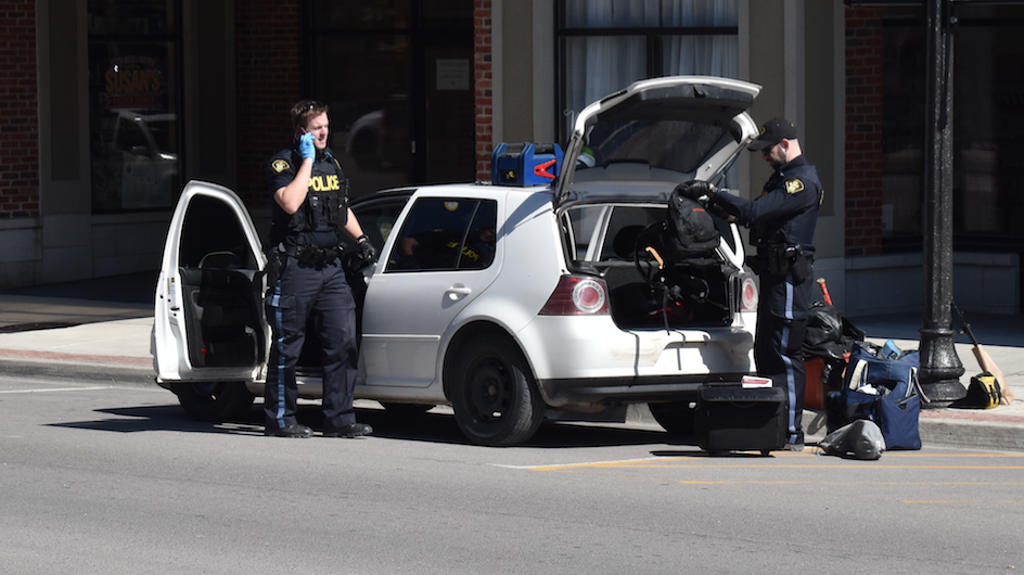 <p>STOP AND GO- Provincial Constables (From left) Aaron Miller and Marc Daneau search a vehicle on Main Street in Picton Monday afternoon. A quantity of suspected illicit drugs, weapons, cannabis accessible to the driver and unsealed alcohol were found. (Jason Parks/Gazette Staff)</p>
