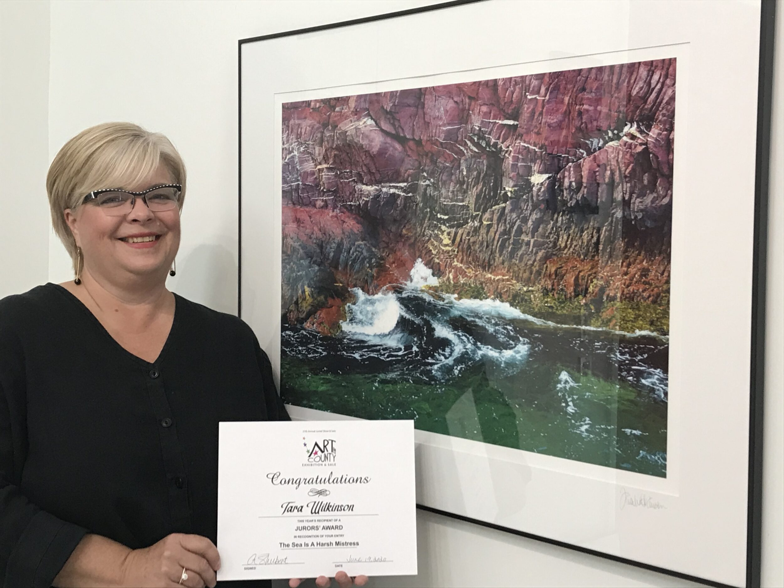 <p>JUROR’S CHOICE- Tara Wilkinson stands next to her work entitled “The Sea Is A Harsh Mistress” which won a Juror’s Choice Award. (Submitted Photo)</p>
