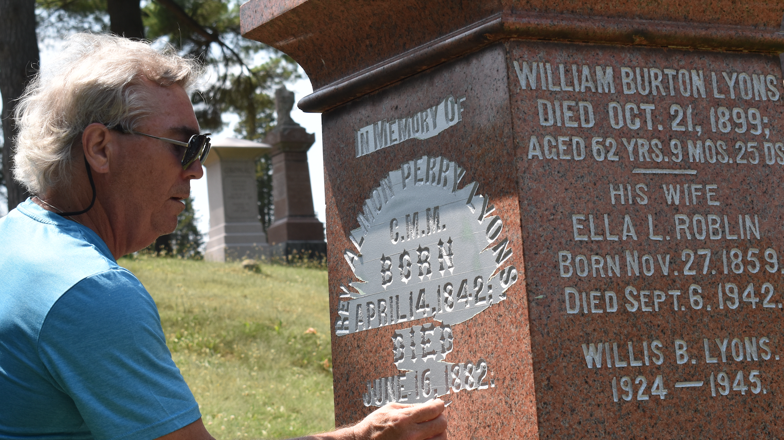 <p>John Lyons peels away covering wax paper to reveal silver inlay on a Lyons family gravestone at Glenwood Cemetery. (Jason Parks/Gazette Staff)</p>
