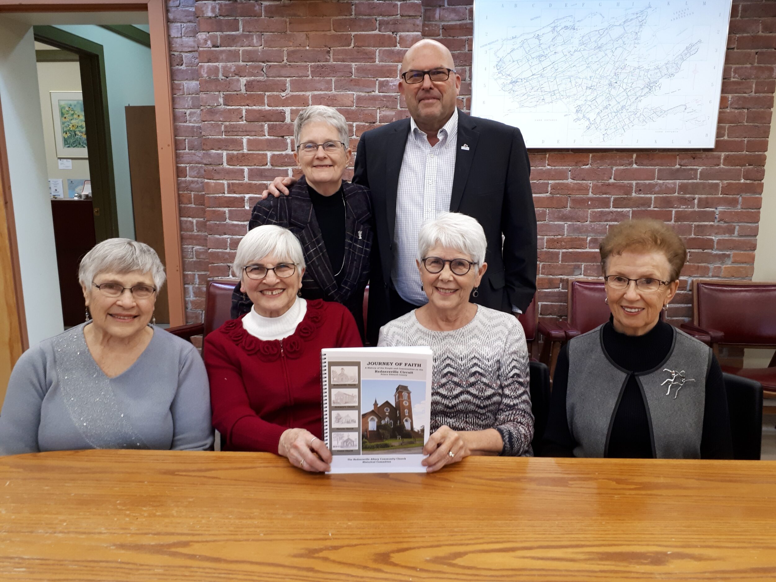 <p>A JOURNEY THROUGH TIME-Prior to the COVID-19 pandemic, County of Prince Edward Mayor Steve Ferguson joined contributors (Seated from left)  Audrey Carter, Evelyn Bedford, Sharon Vanclief, Judith Zelmanovits and (Standing) Sandy Latchford at Shire Hall to celebreate publication of Journey of Faith, a retelling of early Ameliasburgh based around the Rednersville Wesleyan and later United Church circuit. (Submitted Photo)</p>
