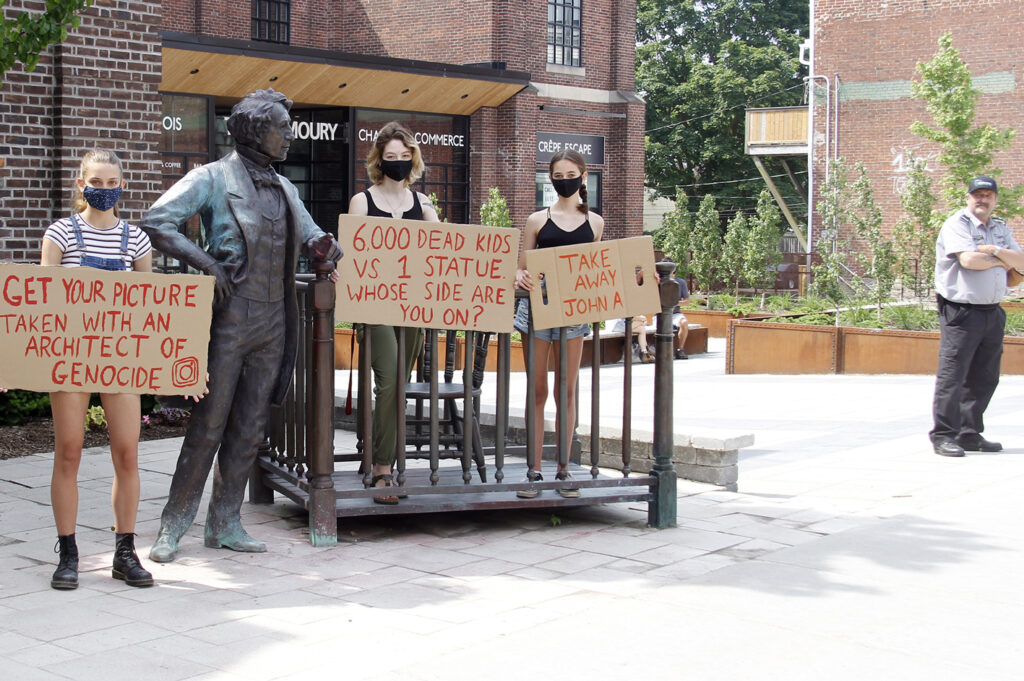 <p>EVERYONE IS WATCHING With a security guard keeping a close eye,  Prince Edward County residents (From left)  Hazel Woodyard North, Talia Epstein and Miriam Epstein display their opposition to Holding Court stationed on Picton’s Main Street Sunday afternoon. On Monday night County Council voted to remove the depiction of Sir John A. Macdonald from its current location until a “more appropriate public location” is determined.  (Desirée Decoste/Gazette Staff)</p>
