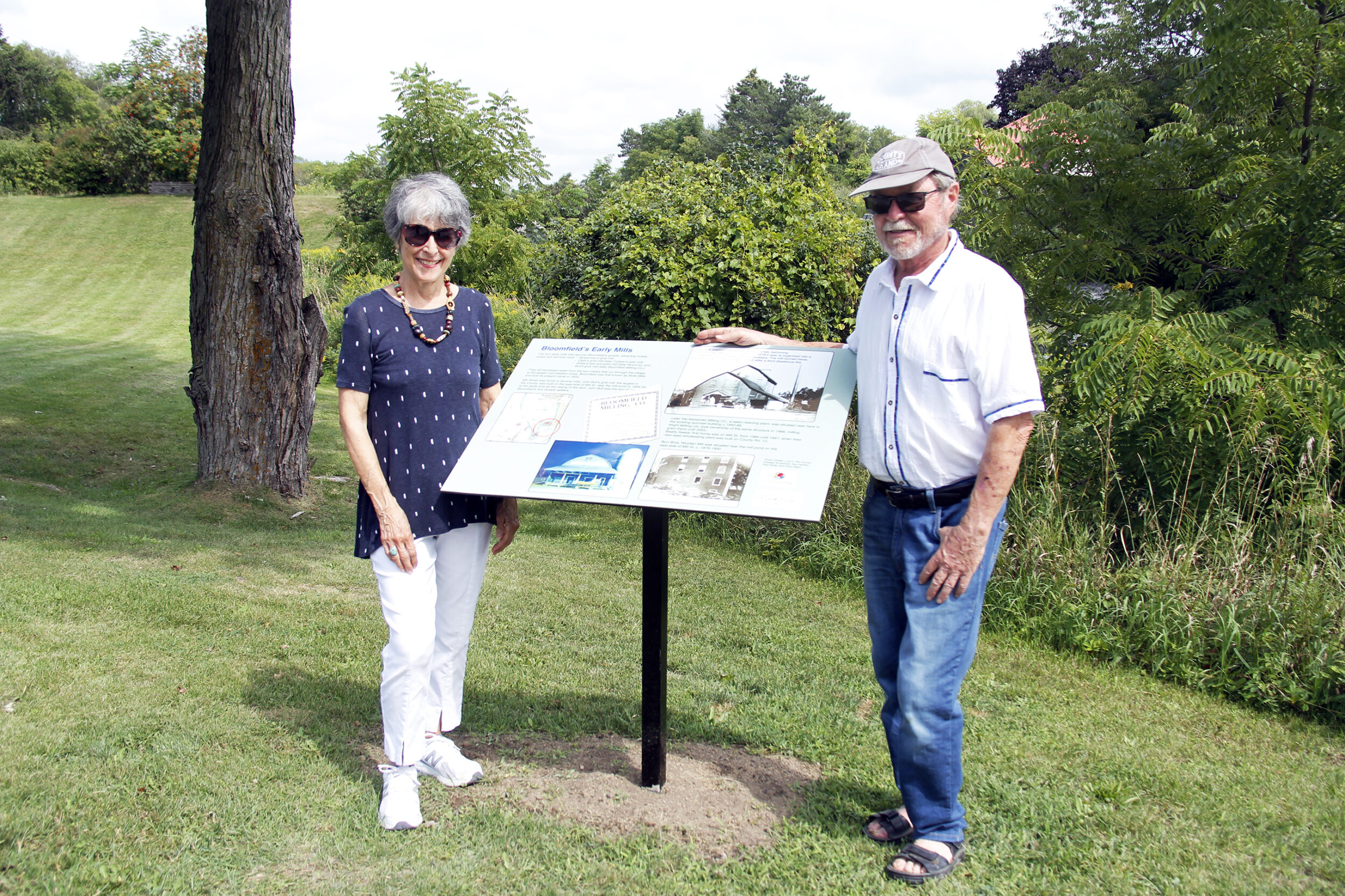 <p>Standing with one of the eight Interpretive History Panels installed in Bloomfield recently (left) Barbara McMullen, one of the leaders in having the interpretive history panels installed, and did the research which provided the information on the panels, and (right) Rob Leek, past president of the Bloomfield and Area Business Association (BABA). (Desirée Decoste/Gazette staff)</p>
