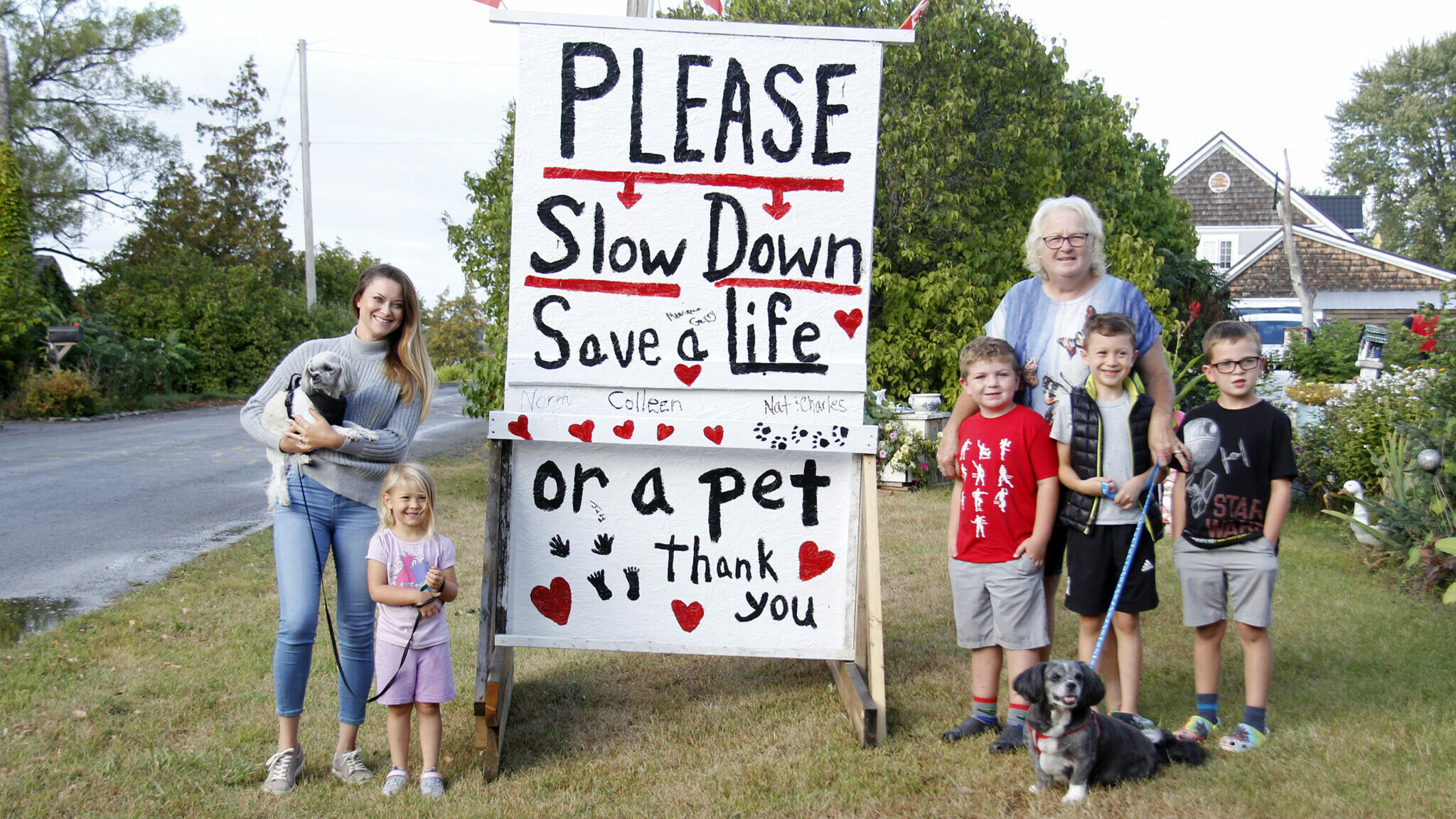 <p>SLOW DOWN Residents of Ridley Street in Rossmore (left) Mihaela Pal, Annaliese Bostock, (back right) Colleen Allchurch, Everest Horrocks, Austen Bostock and Maverick Horrocks stood with the 4&#215;6 foot slowdown sign that Allchurch and her husband created for the street. (Desirée Decoste/Gazette staff)</p>
