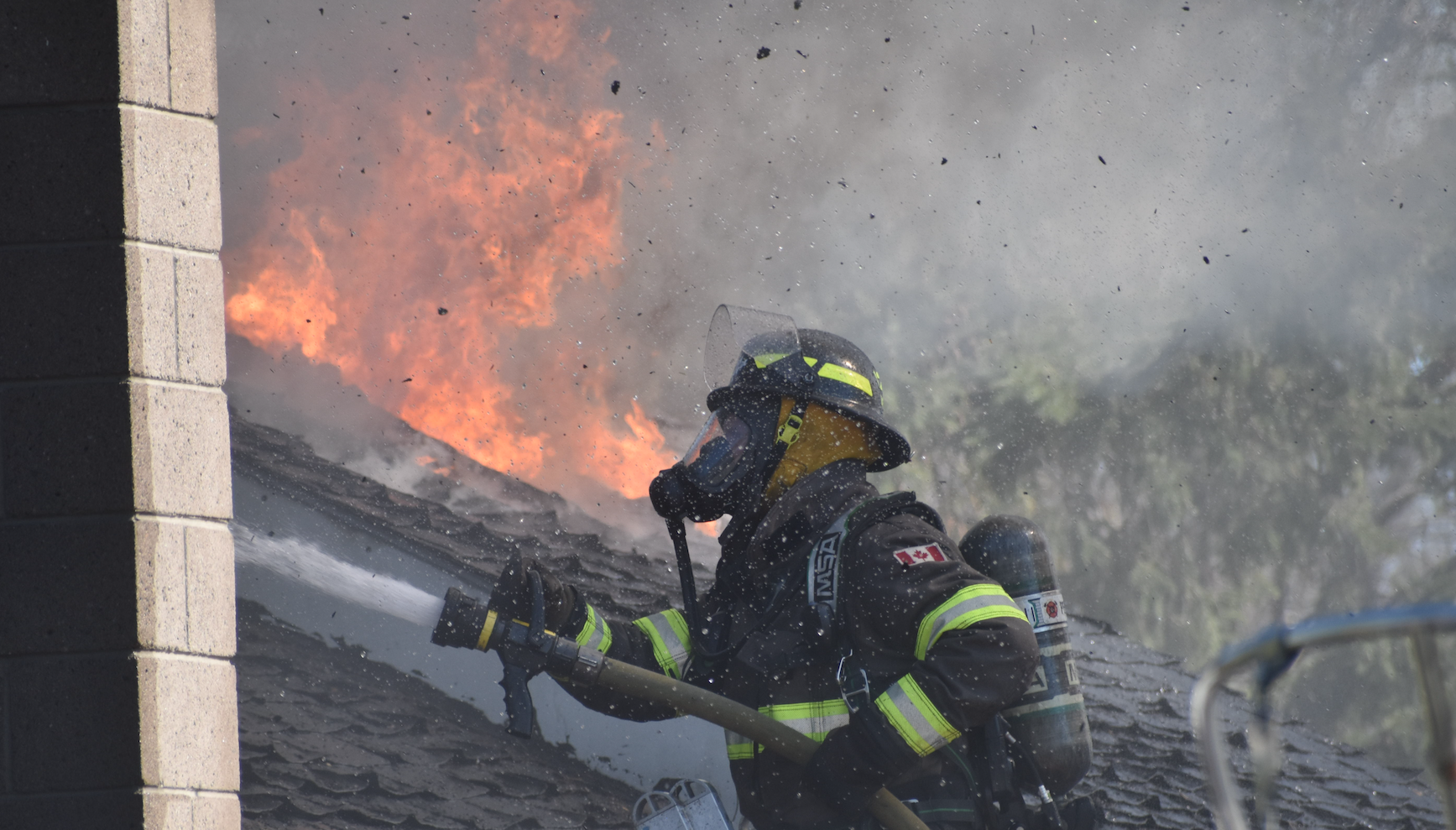<p>Asphalt shingle particles fly as a member of Prince Edward County Fire Rescue douse a roof with water Sunday afternoon. (Jason Parks/Gazette Staff)</p>
