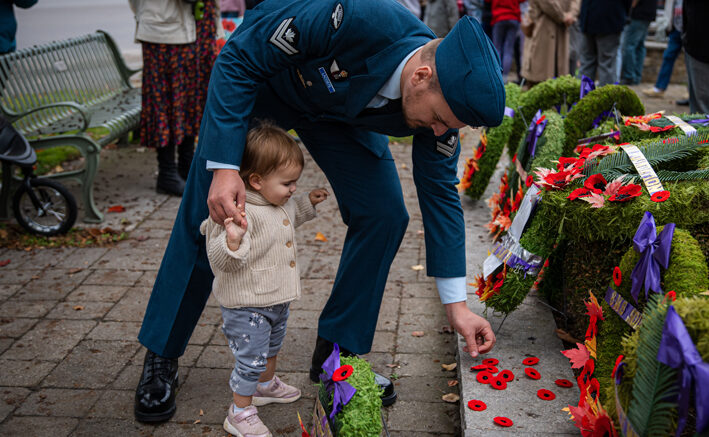 <p>Master Corporal Nick Lacoste from 8 Wing Trenton gets assistance from his daughter, 17 month old Athena, laying a poppy at the base of Picton’s Cenotaph on Friday morning. A good number of community members attended local Remembrance Day ceremonies.  (Ophelia Spinosa for the Gazette)</p>
