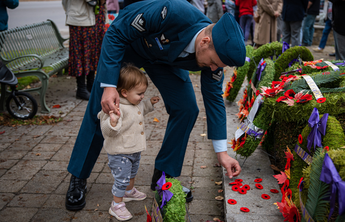 <p>Master Corporal Nick Lacoste from 8 Wing Trenton gets assistance from his daughter, 17 month old Athena, laying a poppy at the base of Picton’s Cenotaph on Friday morning. A good number of community members attended local Remembrance Day ceremonies.  (Ophelia Spinosa for the Gazette)</p>

