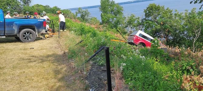 <p>Prince Edward County Fire and Rescue responders work to secure a truck that hd crashed through fencing at the Lake on the Mountain parking lot Saturday morning. (Photo by Dave Sutherland)</p>
