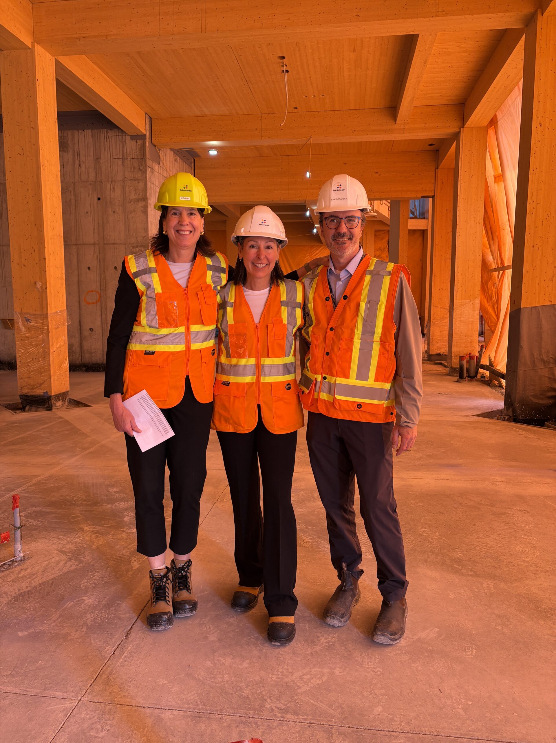 <p>Quinte Health President Stacey Daub, Hospital Foundation Executive Director Shannon Coull, and Quinte Health’s Director of Facilities Chad Cranley show off a just-poured cement floor, marvel at what will be massive, double-height glass walls, and point out the gorgeous timber ceiling in Picton’s new hospital.<br />
(Karen Valihora/Gazette Staff) </p>
